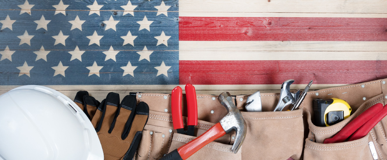 tools, gloves, and a hard hat over a wooden american flag
